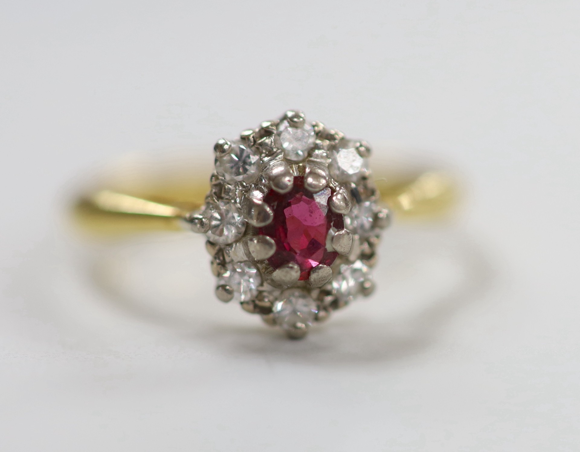 A modern 18ct gold, garnet? and diamond set oval cluster ring, size M, gross weight 3.2 grams.